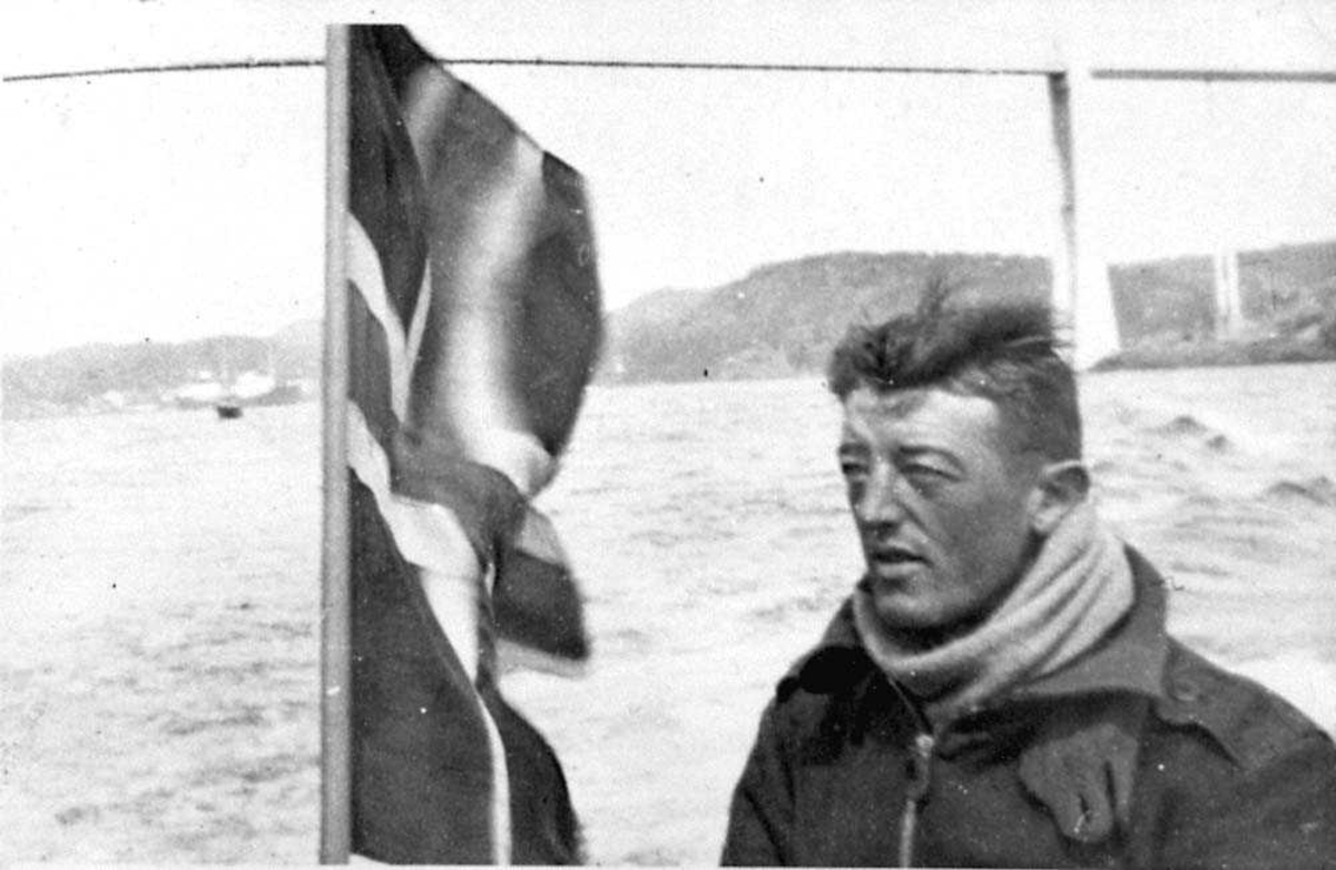Portrett. En person, mann. Ett norsk flagg ved sidan av personen.