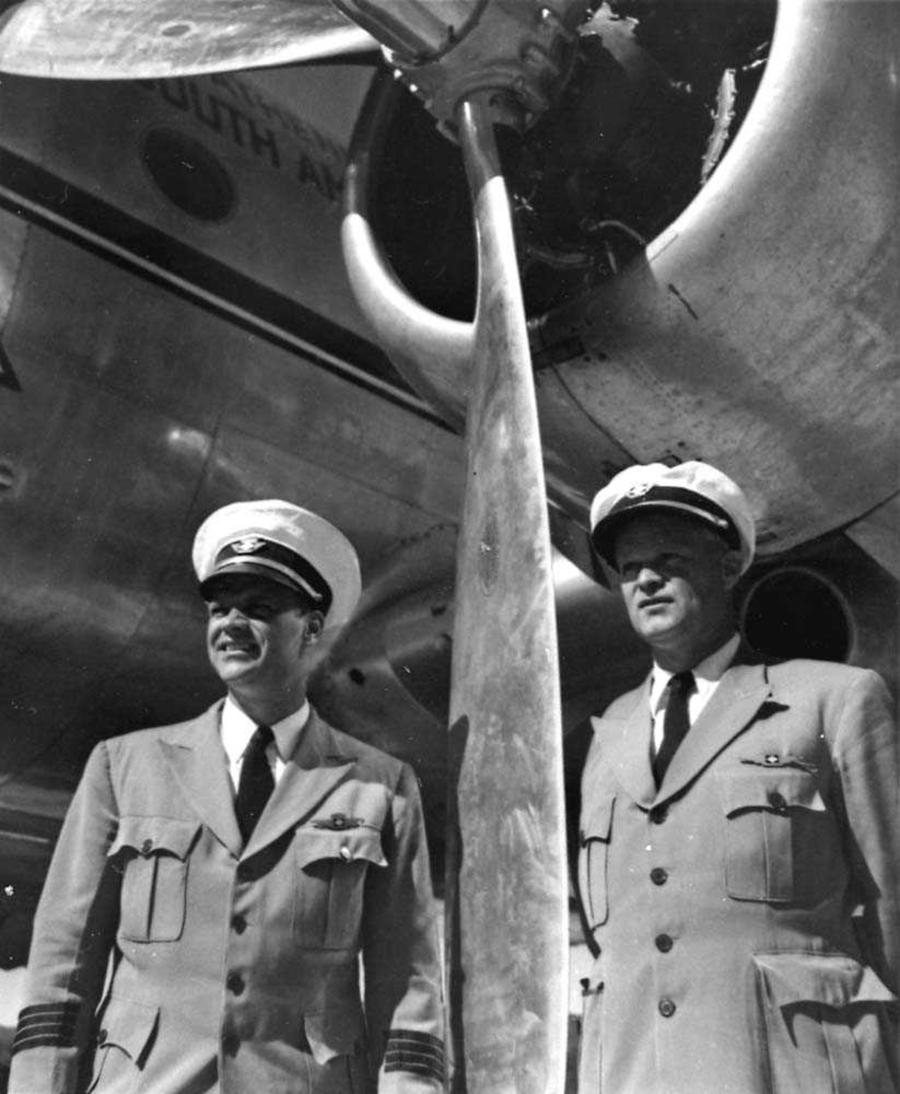 Portrett. To flygere som står foran en av motorene til en DC-4 fra Braathens SAFE.