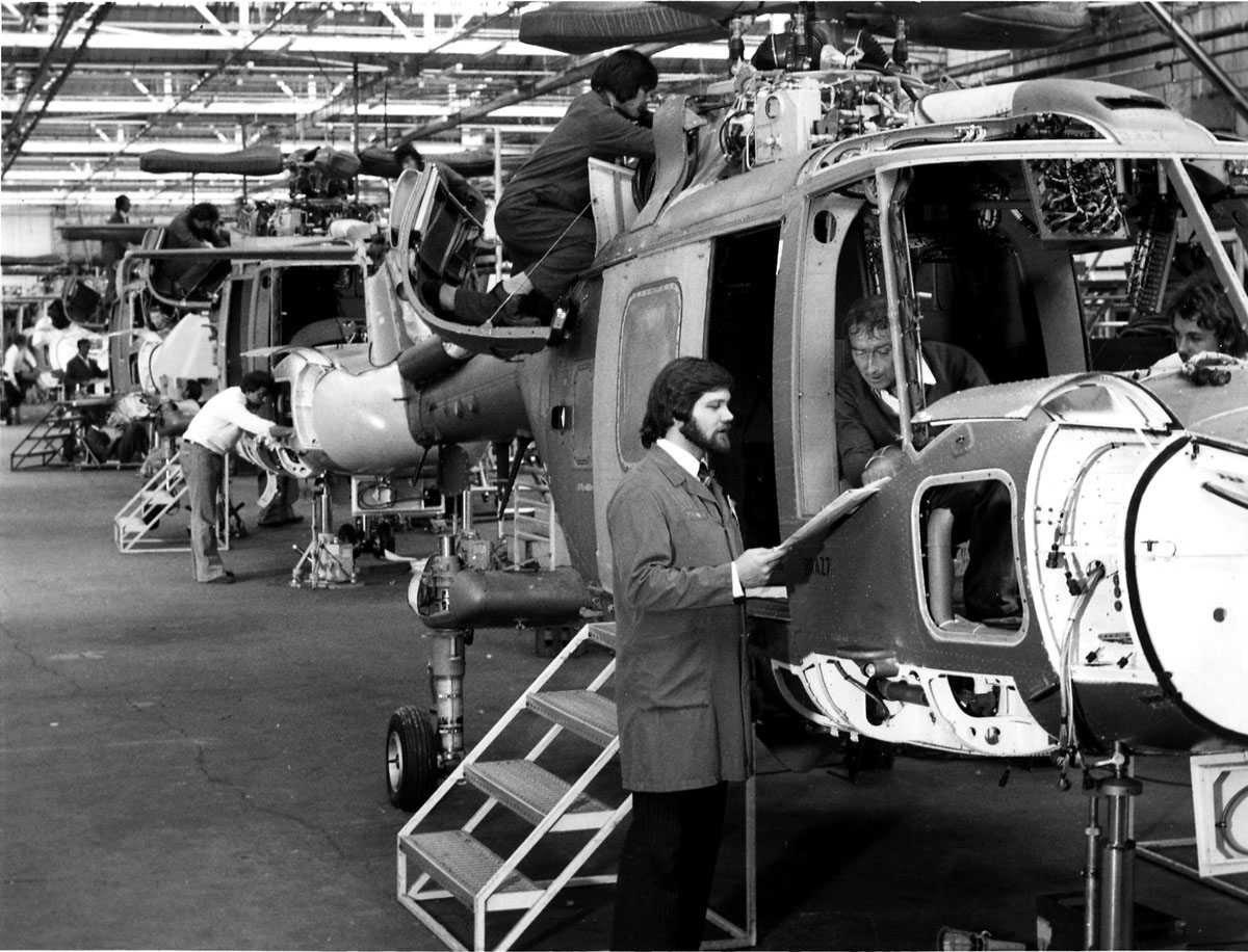 Flere helikoptere i produksjonshall, uferdig. Westland Lynx. Produksjonsmedarbeidere/mekanikere jobber på delvis monterte helikoptere.