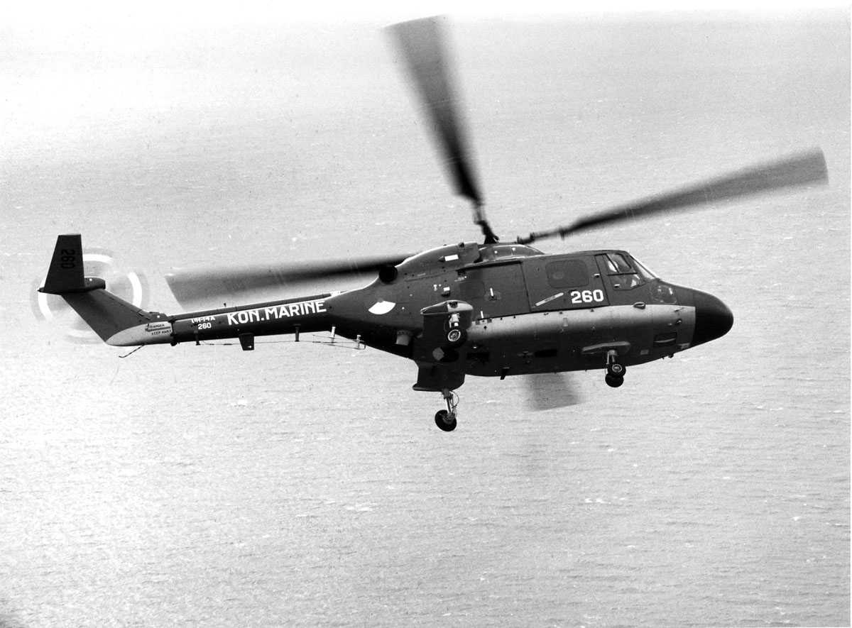 Ett helikopter i luften over sjø, sett fra siden. Westland Lynx Mk.25 (UH-14A), kjennemerke 260 på sidedør og halebjelke. Halebjelke også merket UH-14A KON.MARINE.
