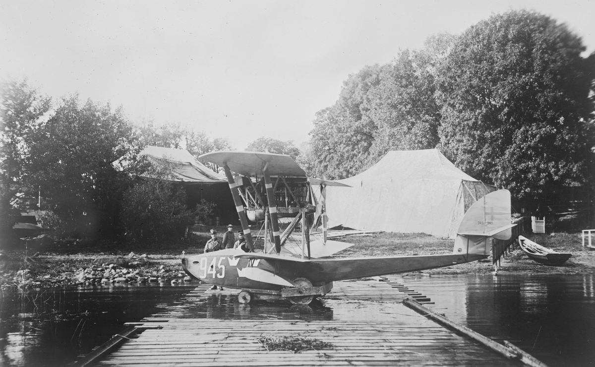 Sjöflygplan Macchi M.7 ur Flygkompaniet vid vatten vid sjöflygstationen i sjön Roxen. I bakgrunden syns personal och tälthangarer.