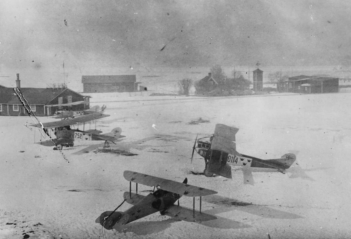 Översikt av tre flygplan Albatros B IIa märkt nummer 752, 874 och 0114 samt Tummeliten 'Hjärter ess' tillhörande Flygkompaniet, vid verkstadsområdet för Flygkompaniet, vintertid.