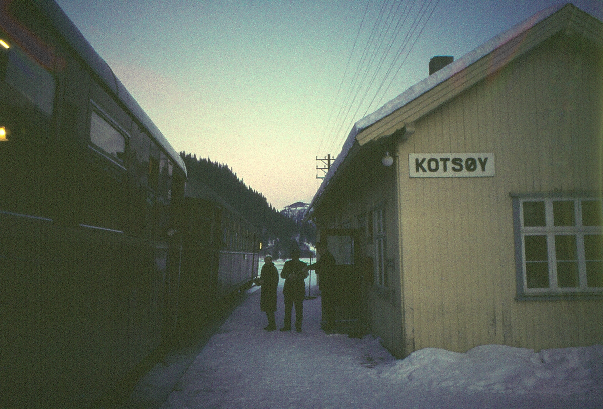 Persontog 412, Røros - Trondheim, stopper på Kotsøy stasjon. Togekspeditør og togfører samtaler, og en reisende skal gå ombord.