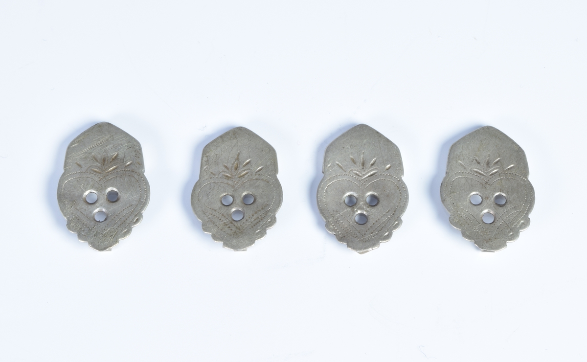 Fire sproter (beslag på den ene enden av belte til folkedrakt fra Setesdal) av sølv dekorert med siselerte sikksakkborder og små blader.
