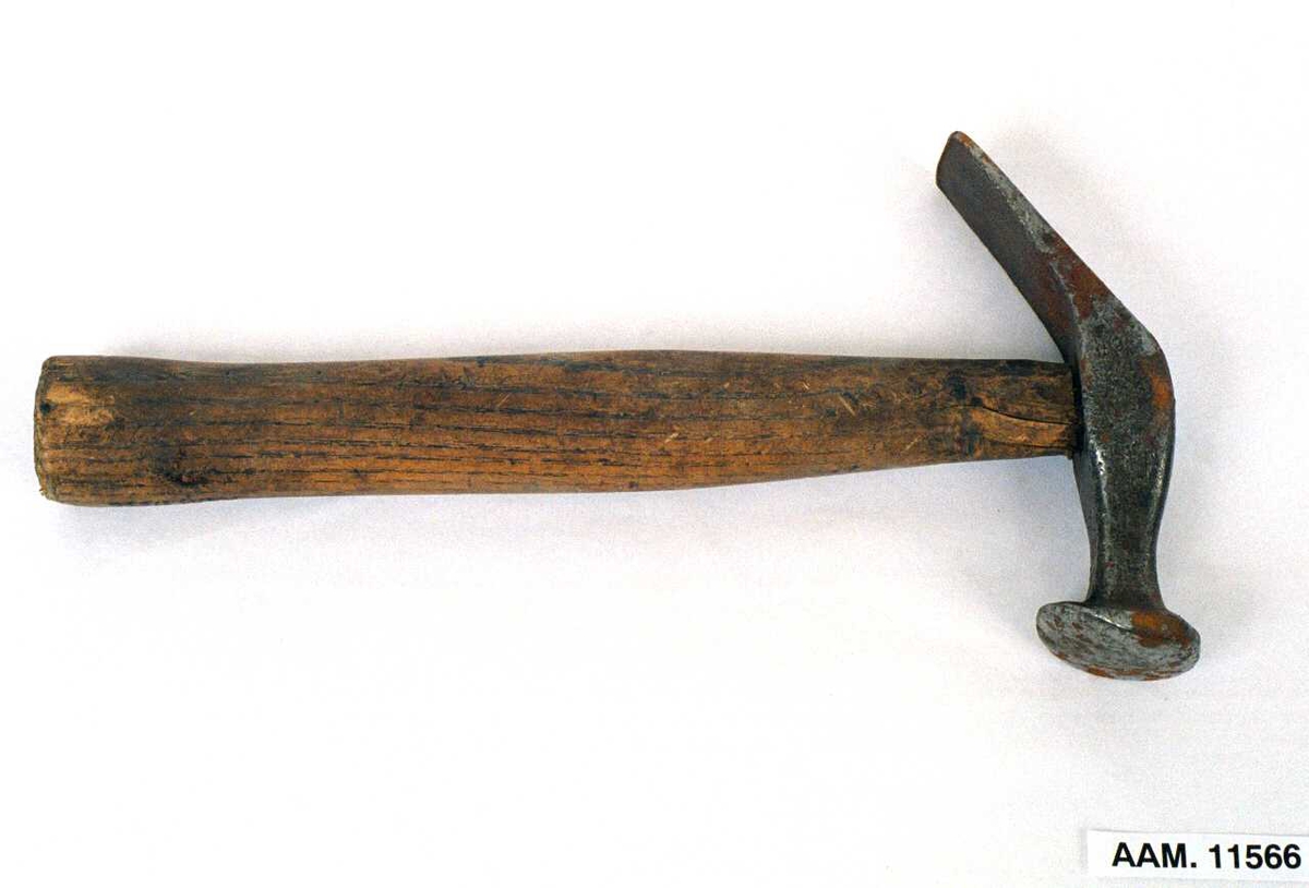 Skomakerverktøy.  Hammer.  Ovalt skaft, smalt hammer med rund slåflate  i en ene ende, den flate ende sterkt nedskrådd  mot skaftet.