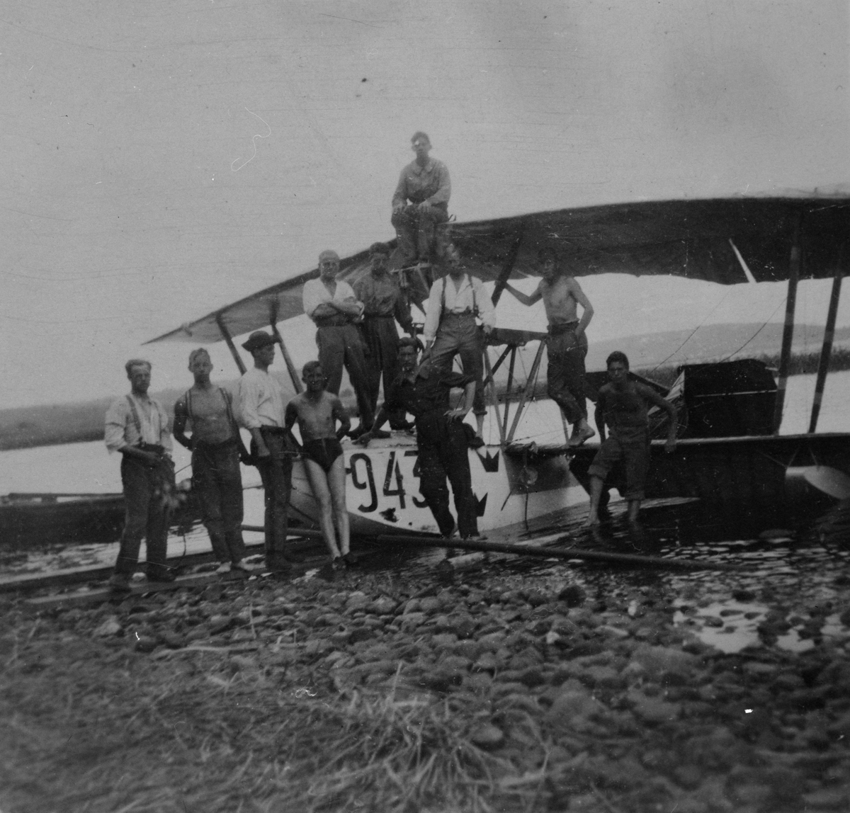 Grupporträtt. En samling militärer står vid sjöflygplan Macchi M.7 märkt nummer 943 på land vid sjön Roxen vid Bergs slussar.