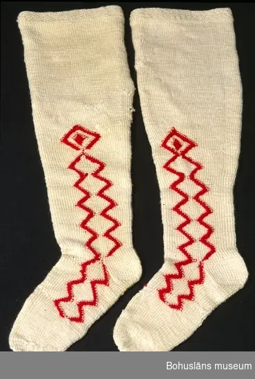 Handstickade strumpor av vitt ullgarn, slätstickade med sicksack-mönster i aviga maskor med rött ullgarn längs fötterna och halvvägs upp på skaften, på både in och utsida. Överst har strumporna en kant mönstrad med aviga och räta maskor. Märkta UM 4:B:I och II.
Enligt Knut Adrian Anderssons katalog I:5:4, D 2 A:1 i museets arkiv, är strumporna "stickade ur minnet av en gammal kvinna på Inland i början av 1900 talet". I samma katalog står även att de vita strumporna skänkta 1910 av Bertha Kleberg är stickade av "gummor på Inland".
Små hål på många ställen. Flera lagningar bl a en lagad lång reva på ena skaftet.
Strumporna diskuteras och är avbildade i Centergran (2010) s. 27-28.

Litteratur om Bertha Kleberg och om revitalisering av bygdedräkter:
Arill, David, Bertha Kleberg och Bohusdräkten ur Bohusländska folkminnen Studier och uppteckningar red Arill, David, Uddevalla 1922.
Centergran, Ulla, Folkdräktsrörelsen i Bohuslän och Göteborg, C-uppsats i etnologi, Göteborg 1973, Bygdedräkter bruk och brukare, Göteborg 1996. 
Centergran, Ulla. Bohusdräkter. Tolkningar under ett sekel. Bohusläns museum och Bohusläns hembygdsförbund, nr. 71. Bohusläns museums förlag. Andra upplagan 2010. 
Wistrand P G, Bohusländska folkdräkter ur Fataburen häfte 1 1908.
STÖDTYG FASTTRÅCKLAT INUTI SKAFTEN PÅ BÅDA STRUMPORNA
Omkatalogiserat 1997-03-20 VBT

Enligt uppgifter på diarienummer 184/69 KVINNLIGA DRÄKTPLAGG FRÅN BOHUSLÄN TILL UDDEVALLA MUSEUM: Strumporna 4a, 4b, 4c är stickade av gummor på "Inland" i början av 1900-talet. ...

Ur handskrivna katalogen 1957-1958:
Strumpor 3 par.
a) Ett par  a) 1-2 L. c:a 62 cm; röda, ylle, stickade m. resår i skaftets översta del; malhål. 
b) ett par b:1-2; L. c:a 67 cm, ylle, vita m. instickade röda kilar; malhål. 
c) Ett par c: 1-2; L. c:a 55; vita, bomull, m. instickade  röda kilar, några rostfläckar. 

Lappkatalog: 78