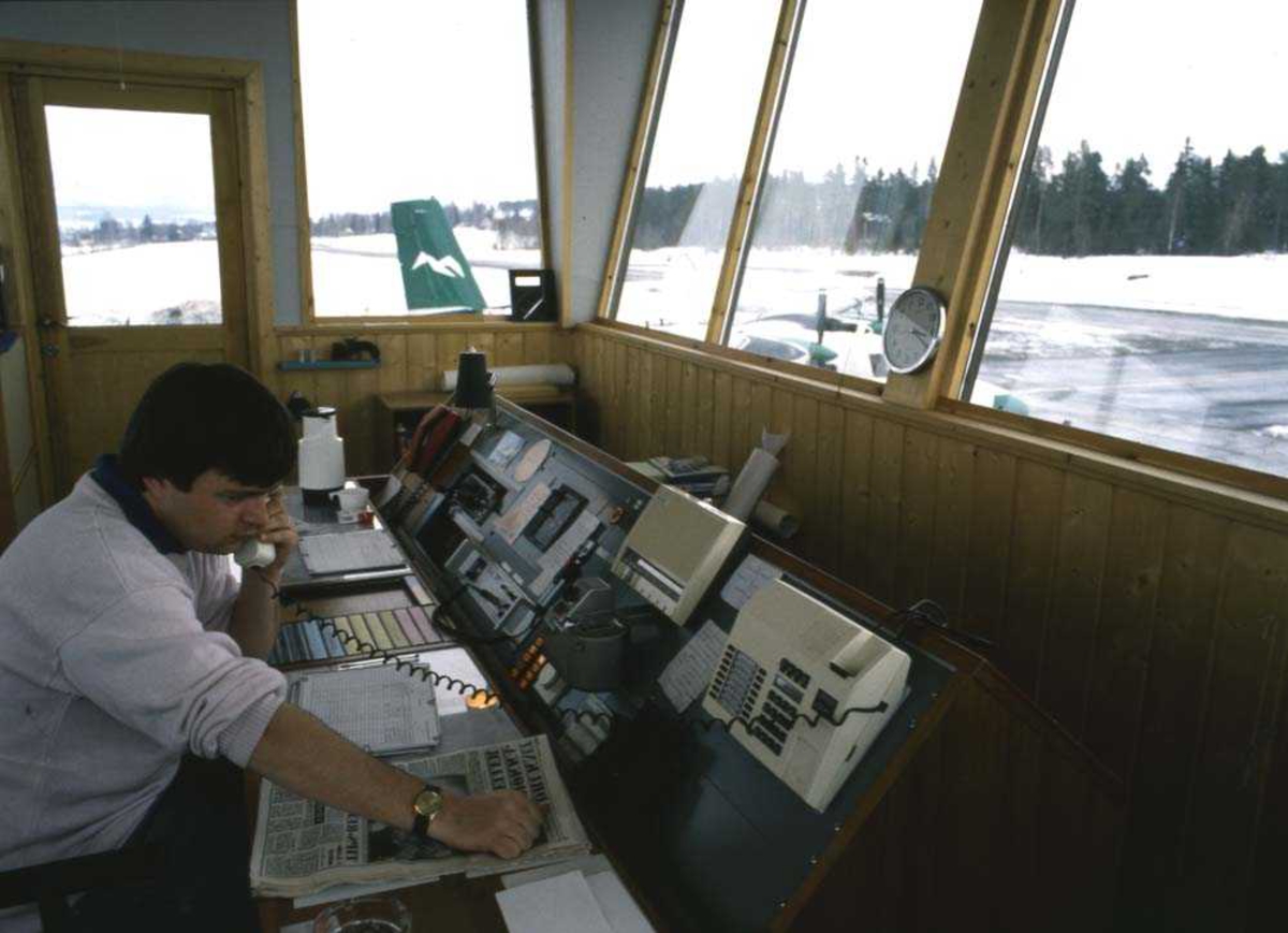 Lufthavn/Flyplass. Mo i Rana/Røssvold. En person,  AFIS-betjent, (Aerodrome flight information service), (lokal flygeinformasjonstjeneste) avbildet på sin arbeidsplass i Flytårnet. 