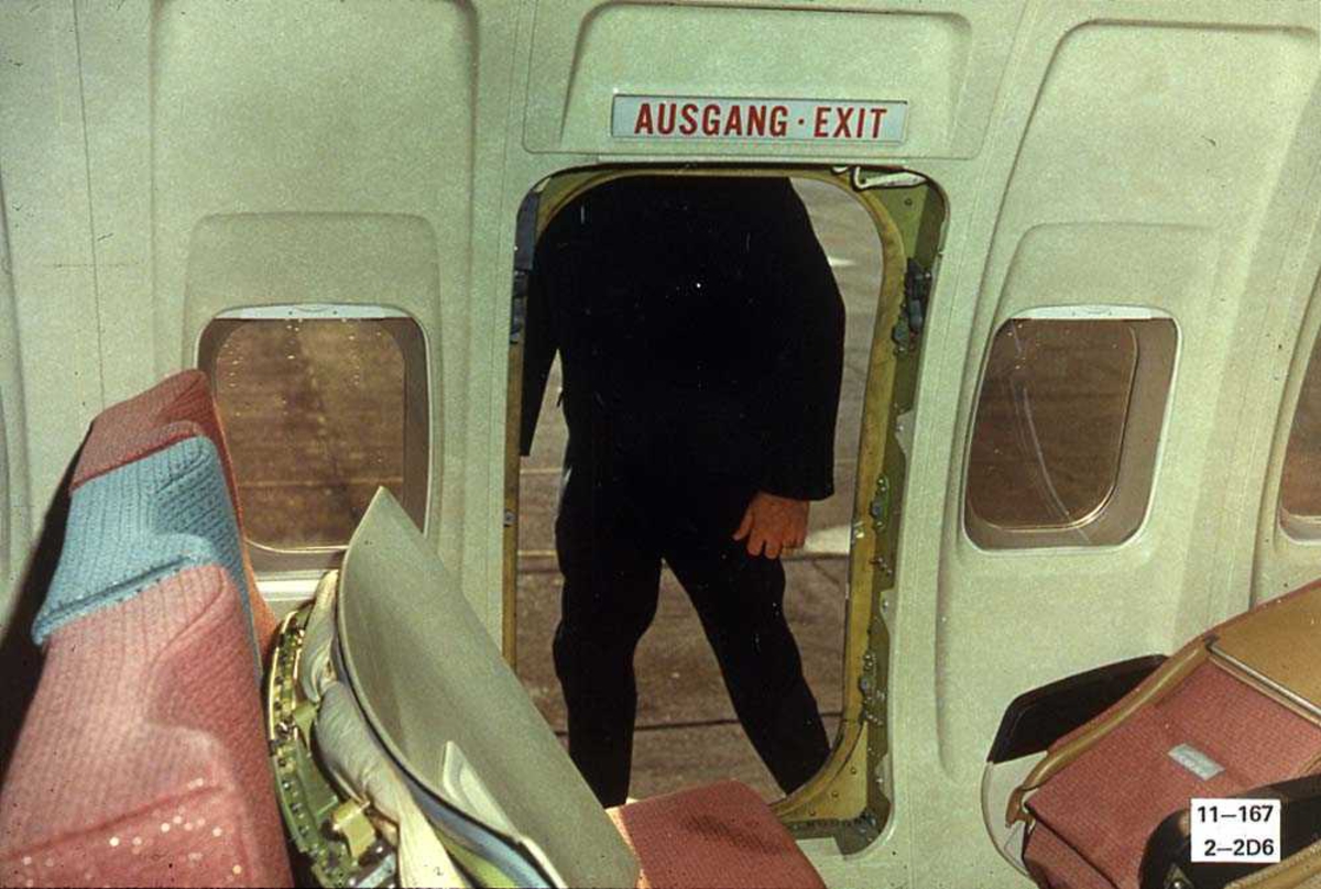 En åpen nødutgang på ett fly, Boeing 737-200. En person på utsiden av nødutgangen.