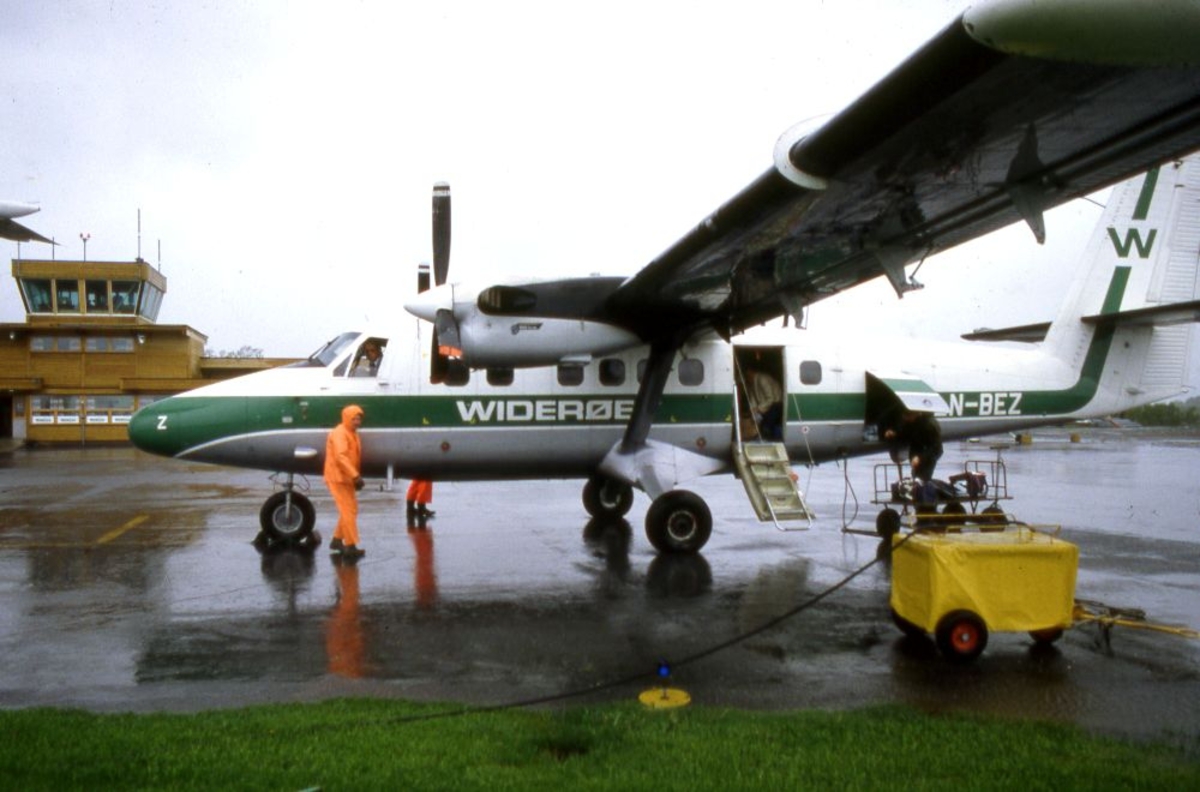 Lufthavn (flyplass). Et fly, LN-BEZ, DHC-6-300 Twin Otter fra Widerøe To personer arbeider på oppstillingsplassen (tarmac).