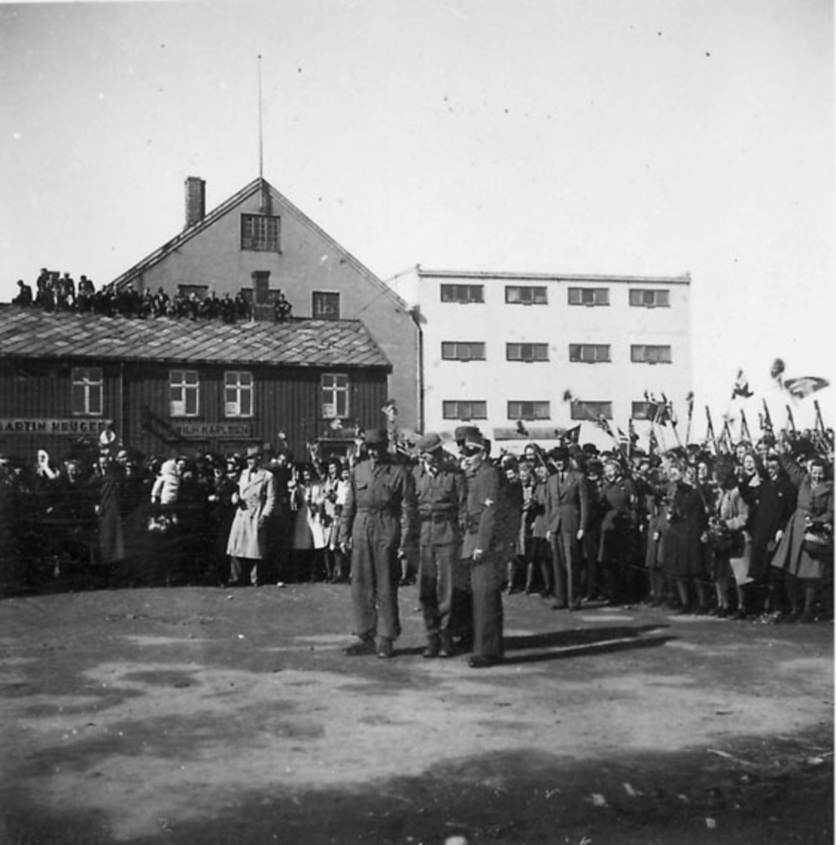 Frigjøringsdagene i Bodø etter krigen 1940 - 1945. Flere soldater og sivile. Flere bygninger, bl.a. med påskrift "MARTIN KRUGER" og "WILH. KARLSEN"