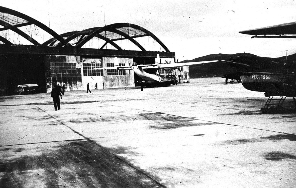 Skattøra  sjøflyhavn, Tre fly står på land. En av dem, Dornier DO 24. Flere personer og to hangarbygninger i bakgrunnen.