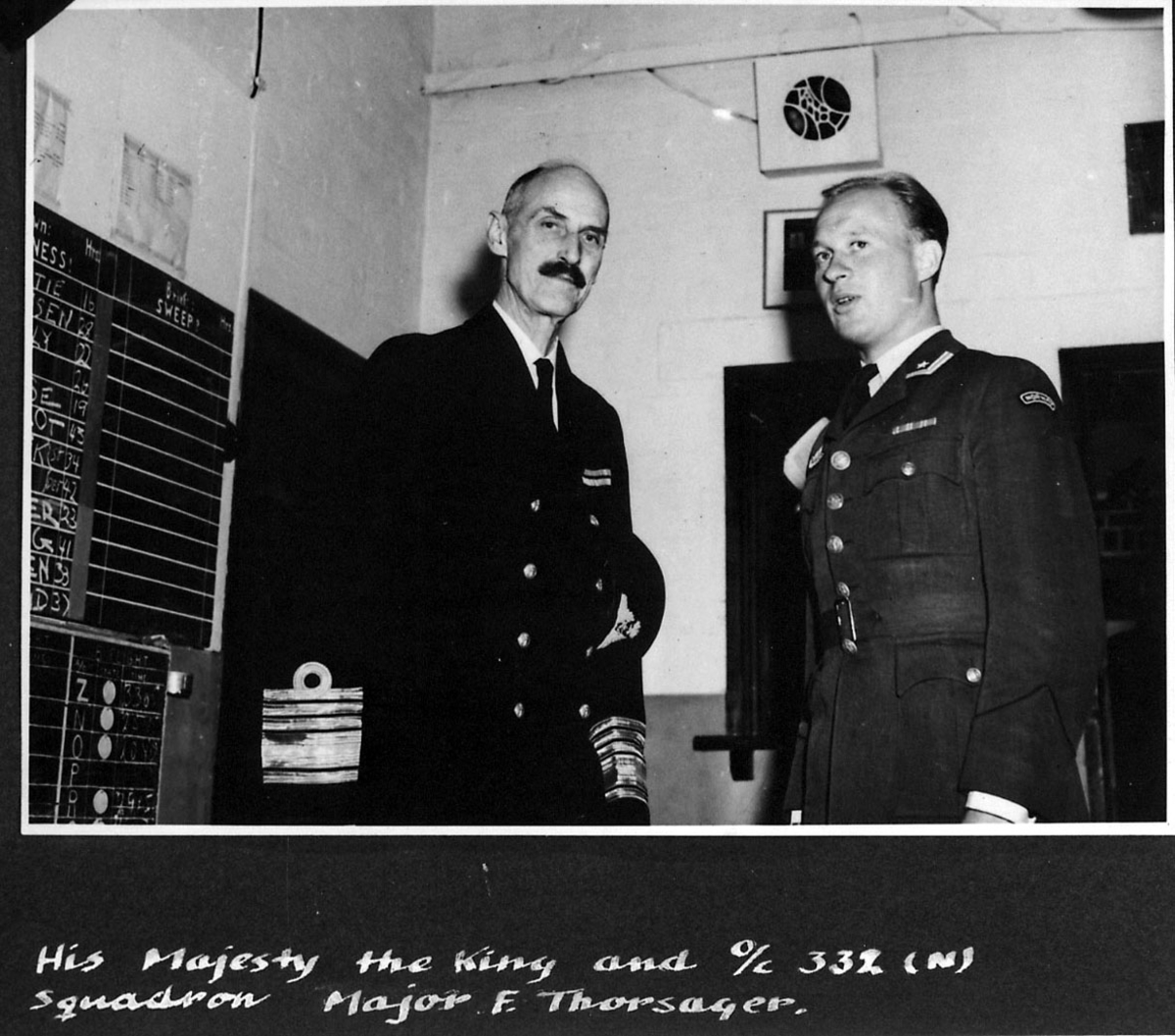2 personer i militæruniform. Kong Haakon VII og Major F.Thorsager. Bildet tatt innendørs. Håndskrevet engelsk tekst under bildet.