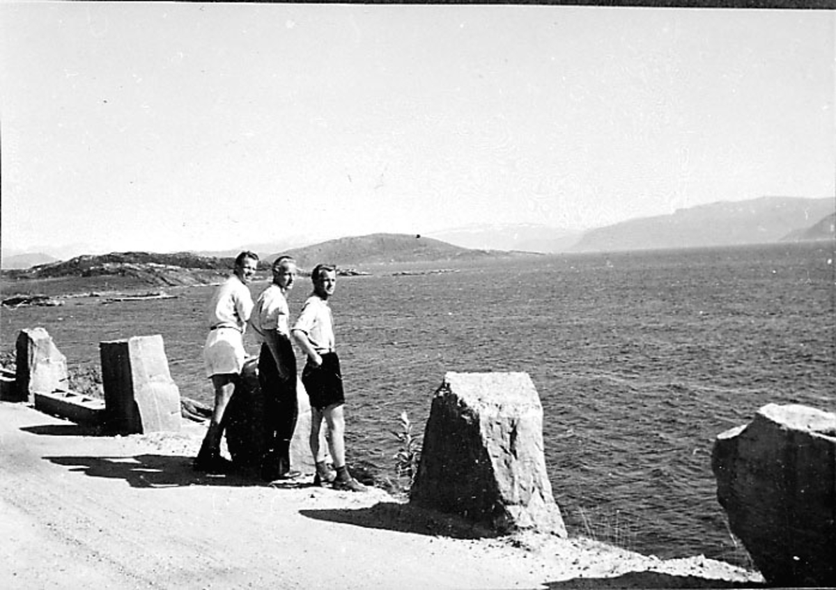 Portrett, 3 personer på en vei, havet i bakgrunnen.