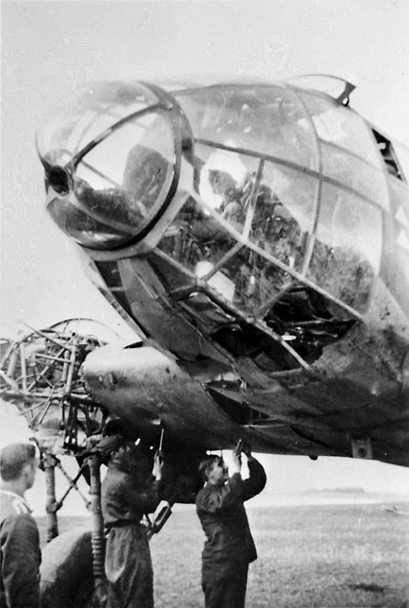 Portrett, 3 personer, tyske mekanikere jobber med å demontere ett fly, Heinkel 111, den ene av dem inne i cockpit.  1 annen person i forgrunnen.