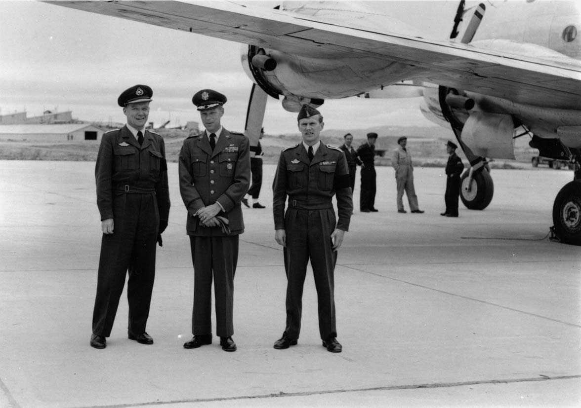 Gruppe  Tre personer i uniform ved siden av et fly.