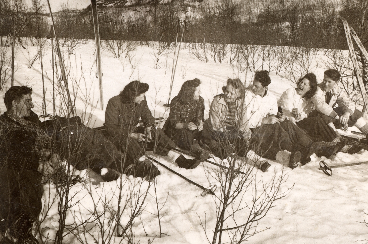 Ungdommer sitter i snøen, omgitt av ski og staver.