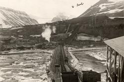Jernbanespor og vogner ved kullgruve på Svalbard. I bakgrunn