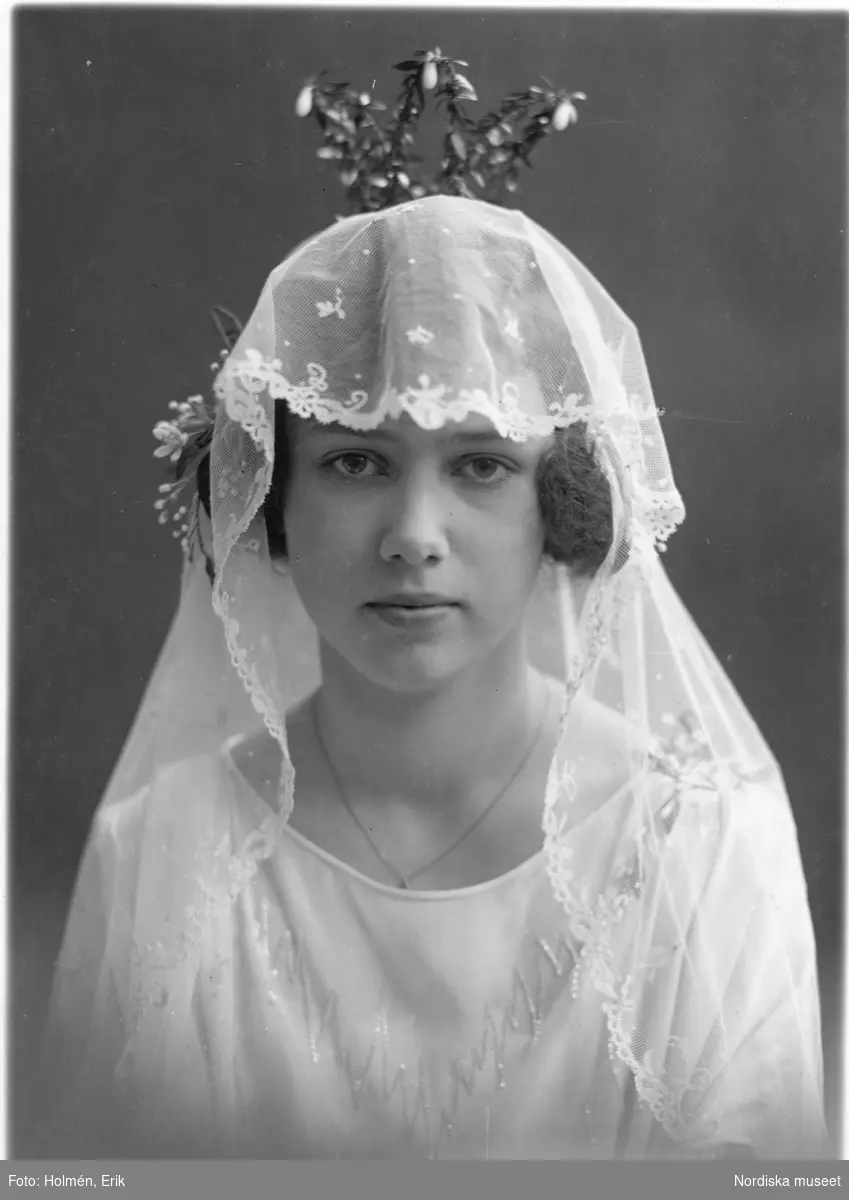Porträtt av en brud i brudklänning, slöja och krona.