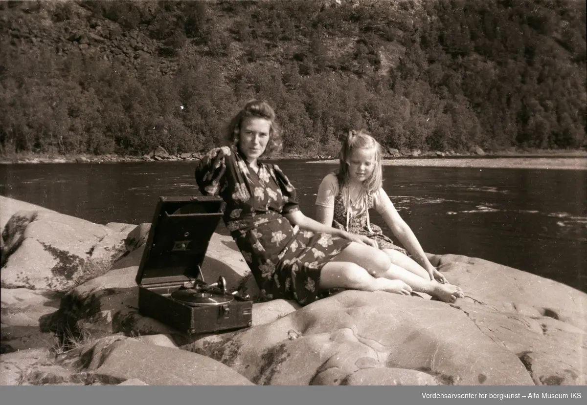 Erna Jøraholmen og Britt Myreng slapper av på berget ved elvebredden, Jorra, sent på 1940-tallet. Grammofonen sørger for god stemning.