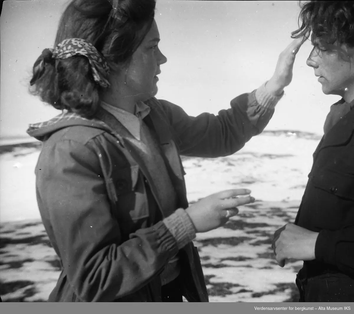 En kvinne fikser hårsveisen til en ung mann, med fjellandskapet i bakgrunnen.