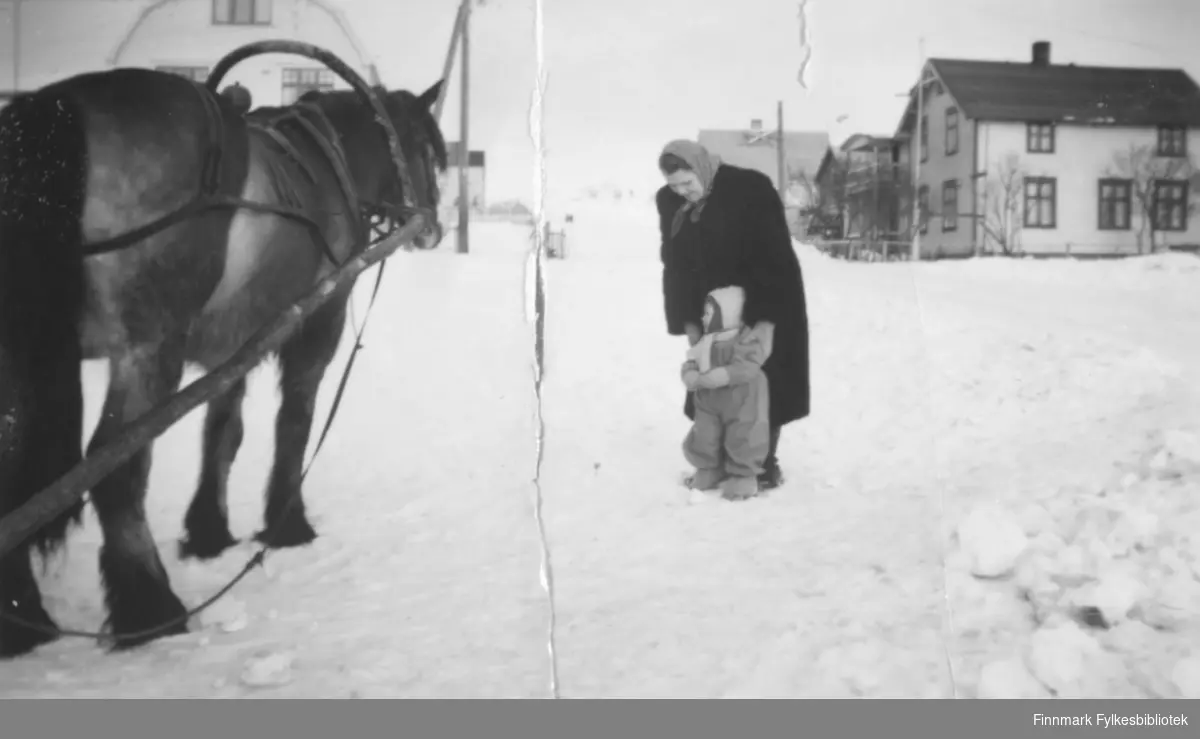 Bestemor Svanhild Kvam sammen med datterdatteren Torill i 1951, de står sammen og ser på en stor hest. Det ser ut til at bygningene i bakgrunnen ligger i Oscarsgate