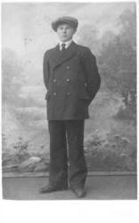 Portrett av ukjent, ung gutt. Han er kledd i jakke, bukse, s