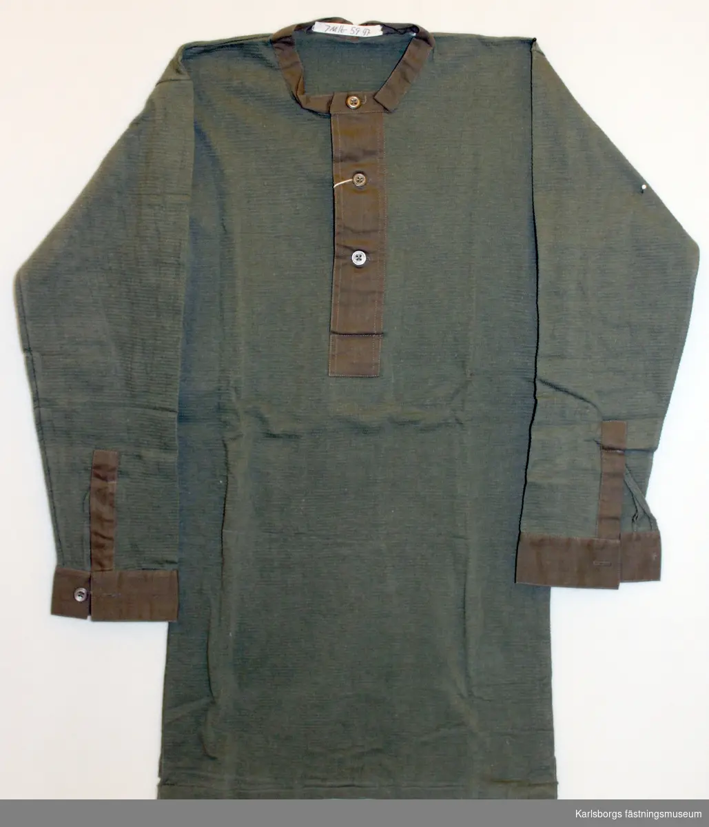 Trikåstickad skjorta med med ärm och halsringning av bomullsband Manschett med ärmsprund av bomullsband.