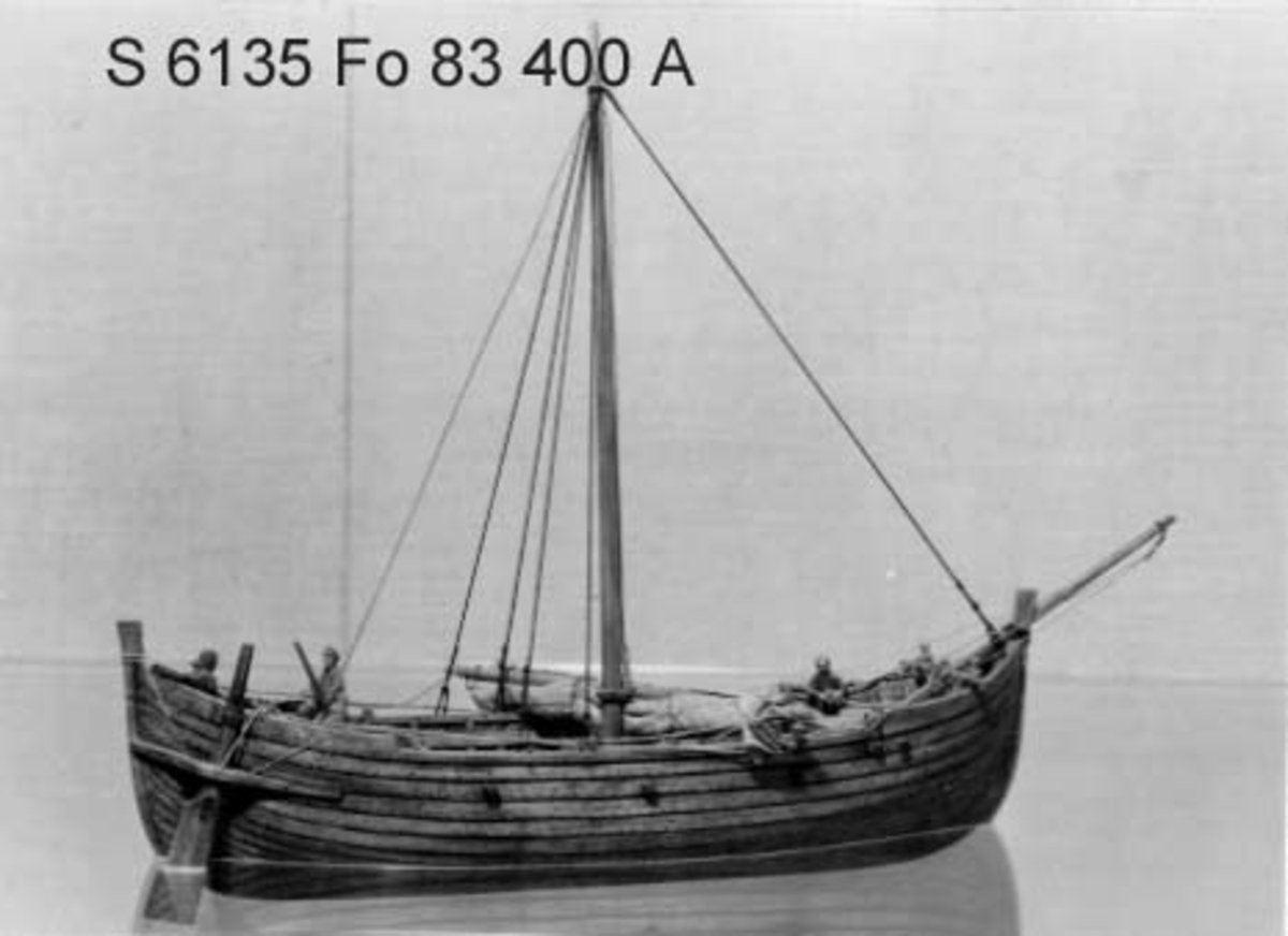 Fartygsmodell av oxelträ, rekonstruktion av Falsterbofyndet, från äldre medeltid. Skrov utfört i två halvor, limmade, bordläggningen skuren. Ankare med tåg och vakare. Träet betsat i tjärfärg.