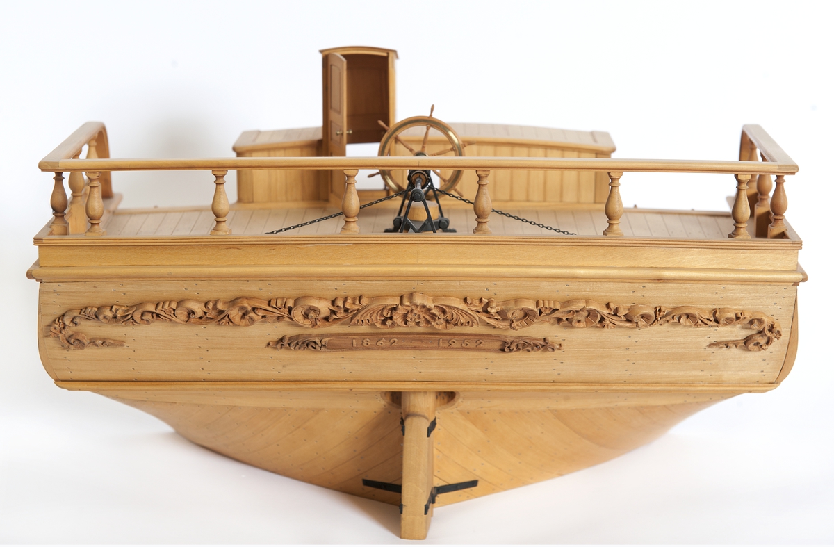 Modell av akterskepp till träsegelfartyg, barkskepp, efter plansch II i Kierkegaard Praktisk Skeppsbyggnadskonst, byggd på klots av al med detaljer och skulptur av päronträ, smiden av oxiderad mässing. Oljad.