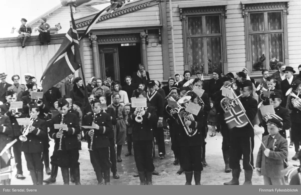 17. mai i Vardø 1952. Bildet av korpset som spiller. Barna i korpset har unifom på. De står og spiller foran et hus.