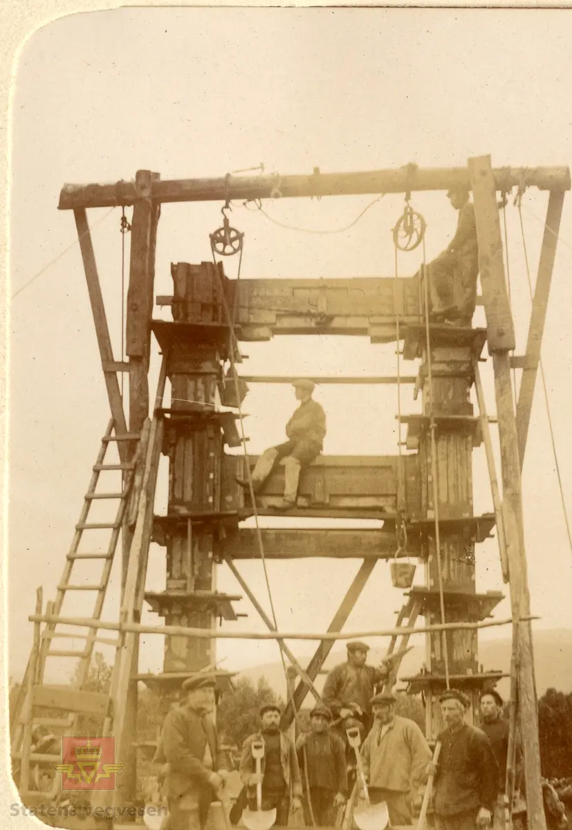 Øvre Salangen bru.  Spennvidde er 54 meter. Bildet viser en gruppe menn i arbeid med brua. Heising av betong i bøtter ved hjelp av taljer og løpehjul. 1913 Øvre Salangen bro stod  på brutårnet da brua var ferdig.