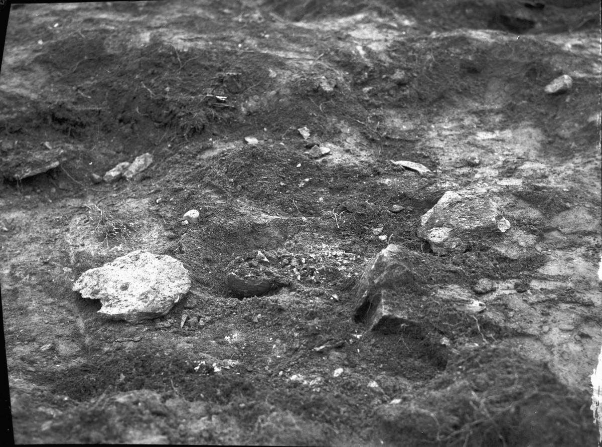 Grav 4 under utgrävning, i mitten synes en anhopning av brända ben och vid sidan därom en större skärva vidare ett vidbuktigt ornerat lerkärl.  S Hillingsäter  Färgelanda