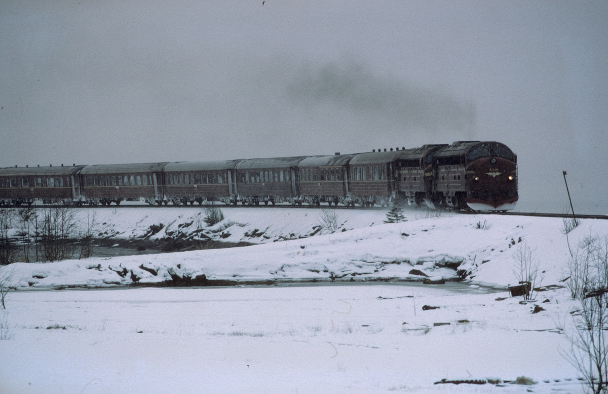 Nordgående dagtog 451 Trondheim - Bodø kjører ut fra Mo i Rana i snøvær. NSB dieselelektriske lokomotiver type Di 3.