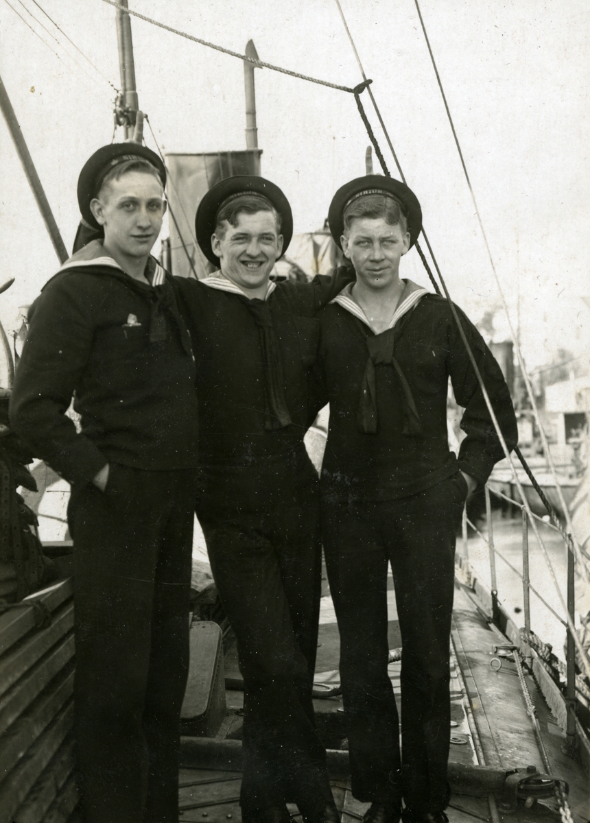 Sjömän poserar ombord ett fartyg, sannolikt en torpedbåt. Gustaf Andersson i mitten. SIRIUS står skrivet på mössbanden.