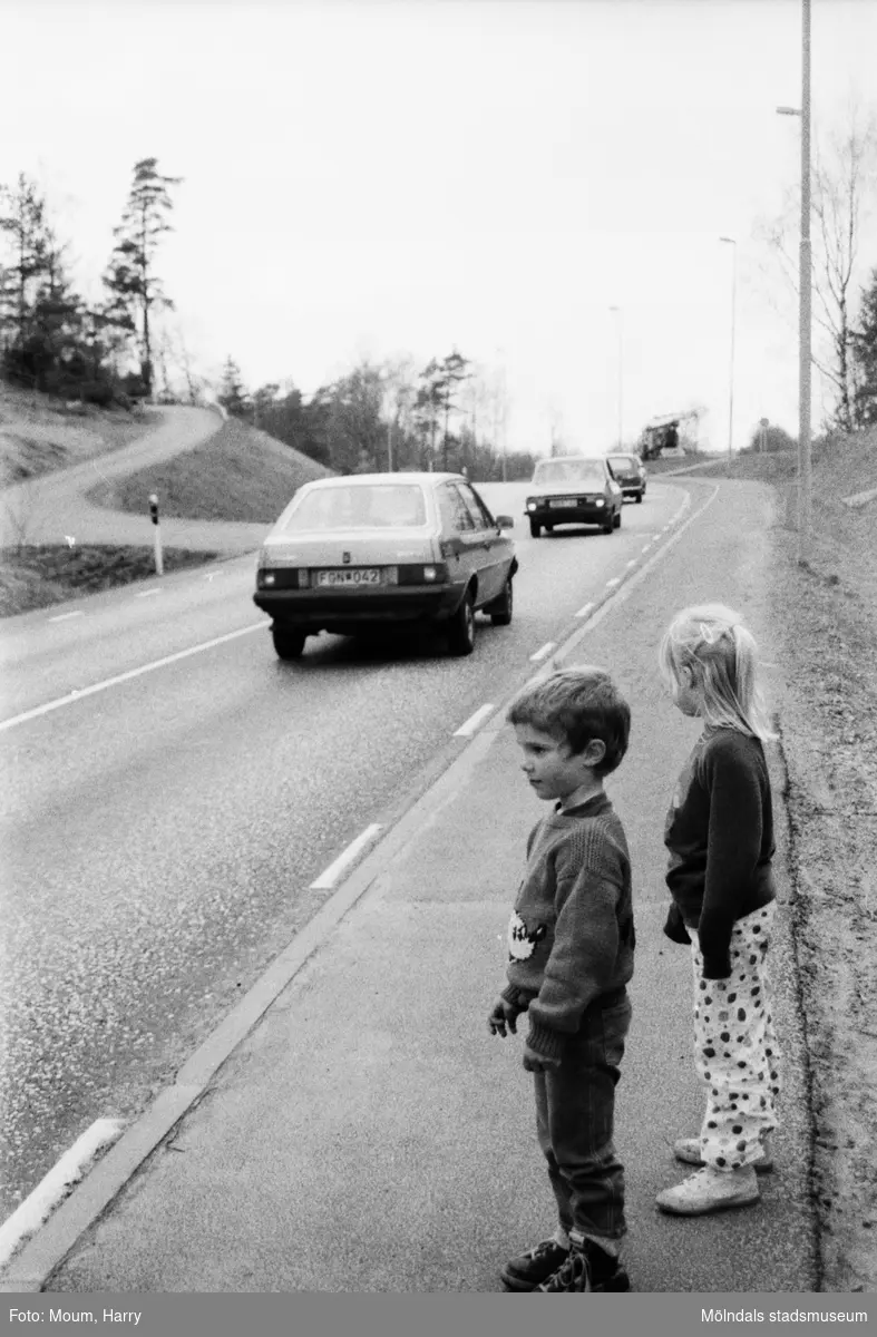 Farlig väg i Kållered, år 1985. "Det är den här vägen som de 31 familjerna i Kållered anser vara en trafikfara och därför kräver åtgärder."

För mer information om bilden se under tilläggsinformation.