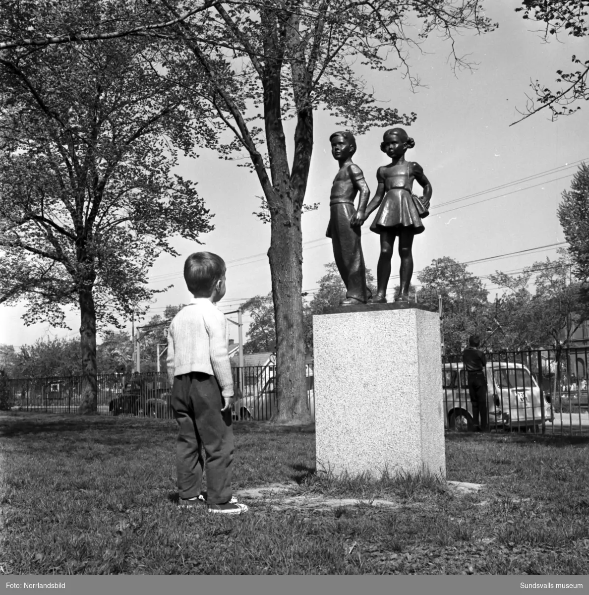 En liten pojke betraktar statyn av de två barnen som pryder Gustav Adolfsskolans skolgård. Bronsskulturen är gjuten 1953 av Jonas Fröding (1905-1959).