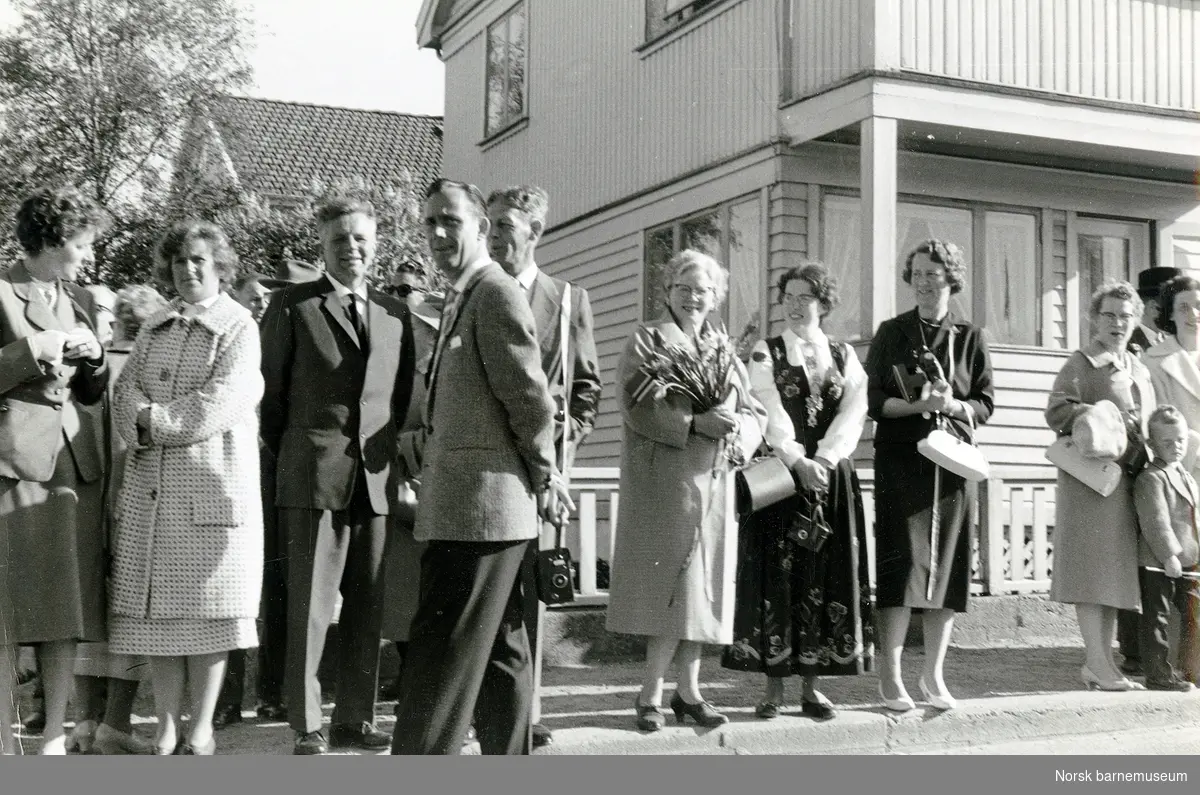 Foreldre venter på 17.maitoget ved Kvaleberg skole, Hillevåg. Kvinnen i bunad er Ingjerd Bull-Njå, gift Sinnes.