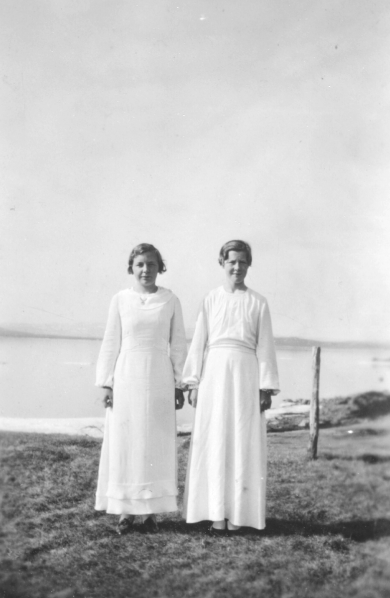 To jenter i lyse kjoler. Bildet er tatt i fjæra. Hun til venstre er Borghild (født Dahl) Løkting 1921-2006 og til høyre står Asbjørg (født Betten) Jakobsen 1921-2016.