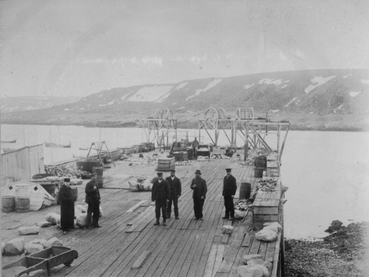 Seks menn står på kaien i Hamningberg i 1905.