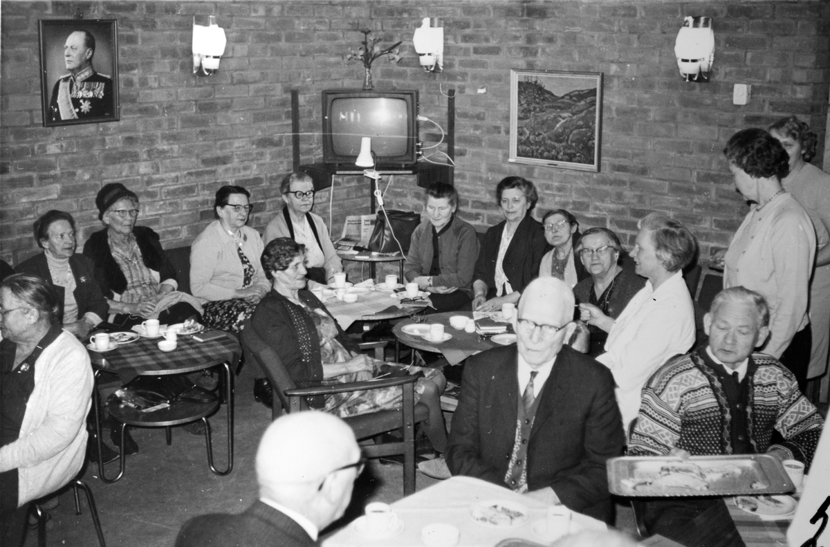 Eldre kvinner og menn drikker kaffe på Soldathjemmet. Til venstre sitter veterinær Louise Iversen, i kvit bluse.
