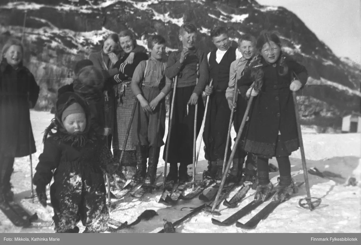 En mengde barn og ungdommer ute i snøen på Mikkelsnes, mange med ski. Fra venstre: Gudrun, Marine, Synnøve, Andreas og Mikkel Mikkola, Arne Karikoski, Åge og Ingrid Mikkola. Den lille jenta i forgrunnen er Herlaug Mikkola