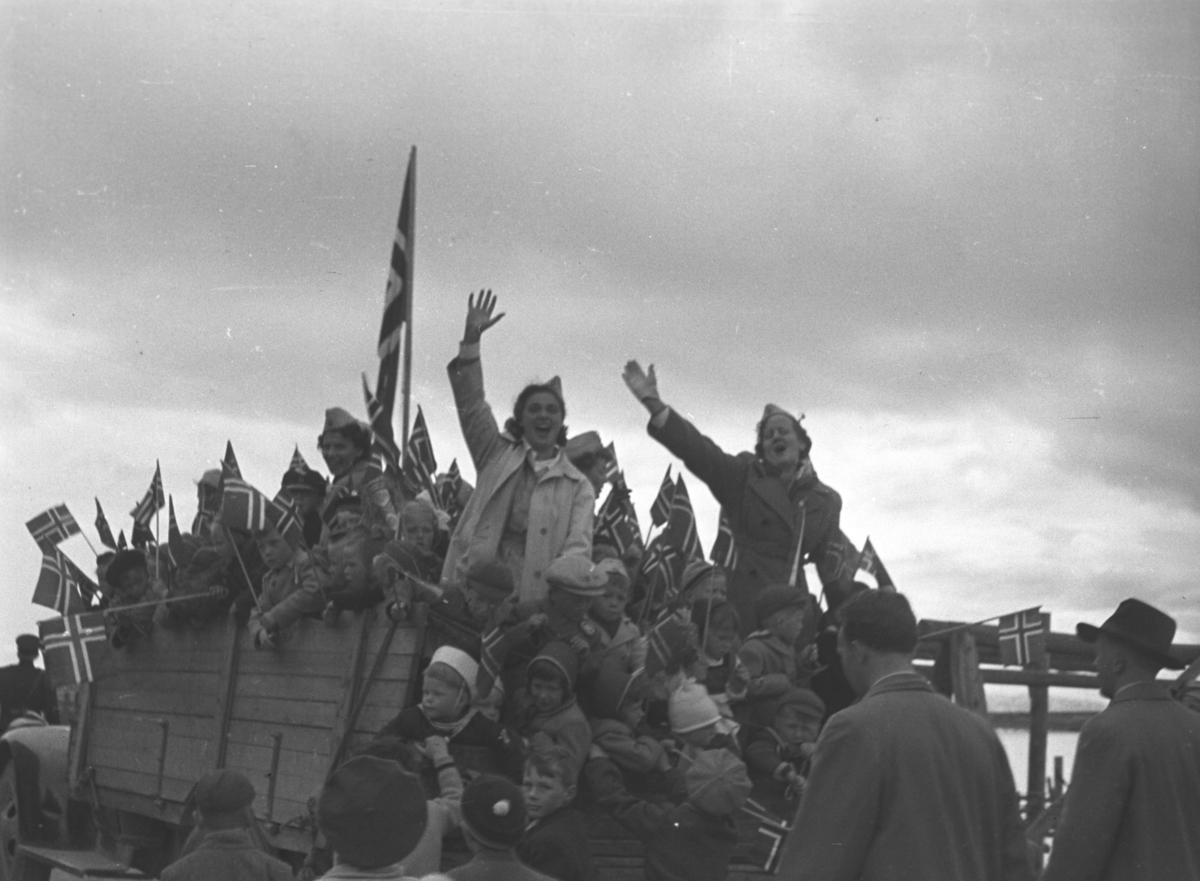 17. mai i feiring Vadsø. Lotter og barn på en lastebil. Damen til høyre på bildet med armen i været er Lisbeth Esbensen. Damen til venstre for det store flagget er Hulda Wara.