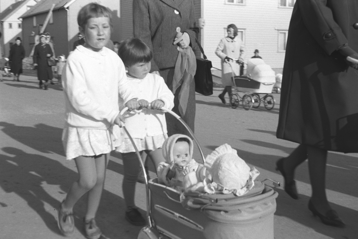 To små jenter triller på en dukkevogn (En Simo fra 1958-59. Den lyse barnevognen i bakgrunn er også en Simo, mulig 1961 modell). Personer og sted er ukjent, men kan være i Vadsø.