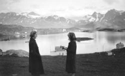 To damer står på en liten slette ovenfor Bergsfjord. Damen t