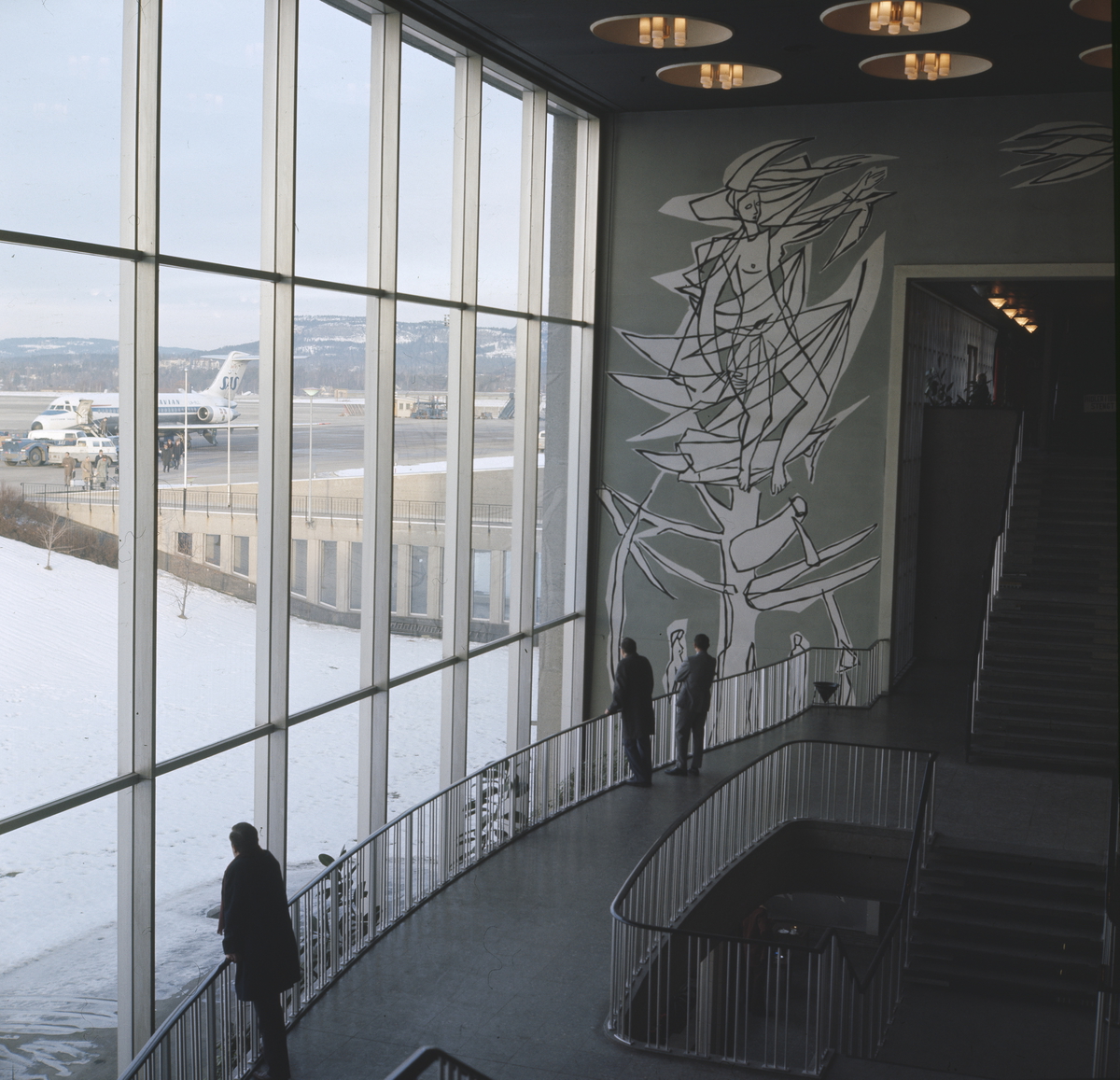 Oslo Lufthavn Fornebu.Tre personer ser ut på flyene.