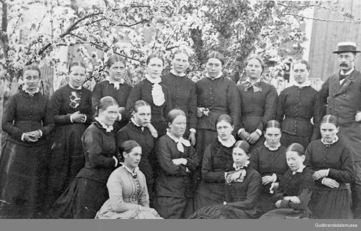 Skoleklasse på atten personer hvorav sytten unge kvinner, oppstilt utendørs, Vestnes.