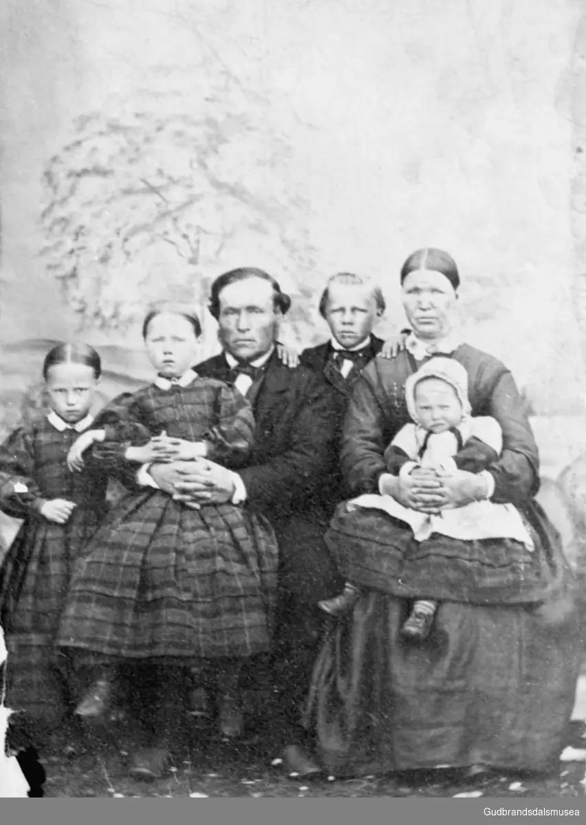 Portrettbilde av familien Bakken, gruppe på seks personer, mann og kone med fire barn, med bakteppe?