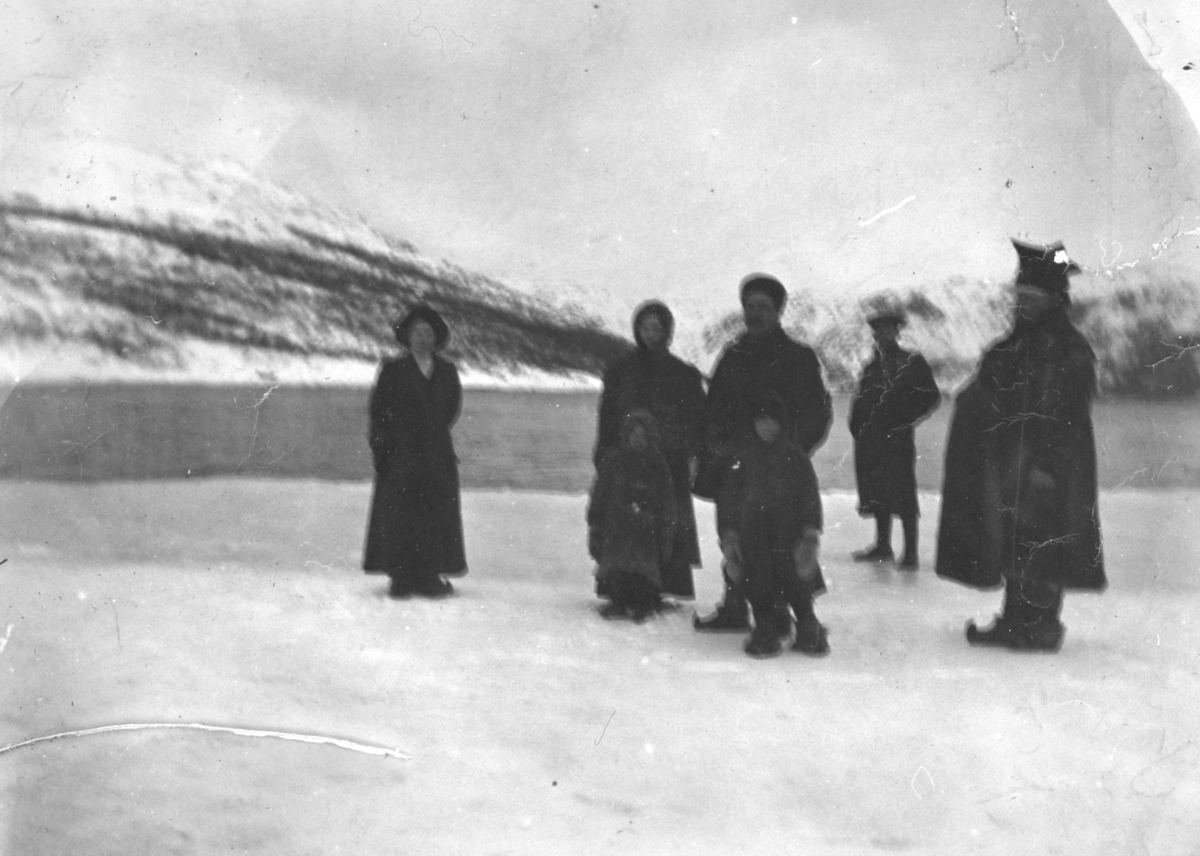 En gruppe folk på isen i Bugøyfjord. Gruppa er kledd i kåper, samekofter og skaller. Mannen til høyre har på seg en samisk lue.