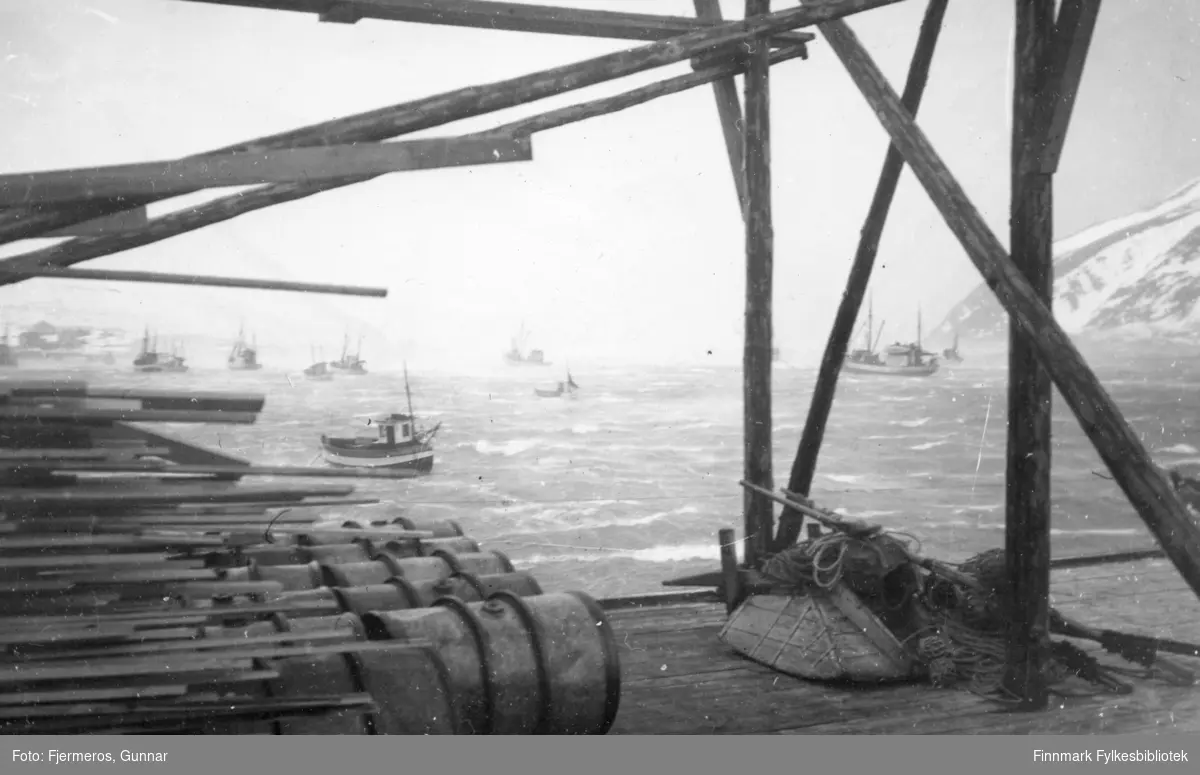 En stormfull vinterdag i Honningsvåg havn i mars 1948. Mange båter ligger fortøyd ute på vågen.